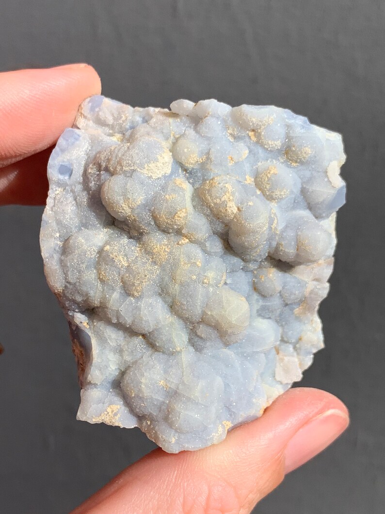 May include: A light blue and white agate geode with a rough, textured surface. The geode has a cluster of small, white crystals.