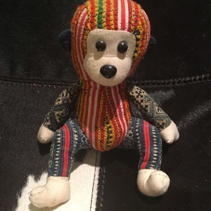 May include: A colorful stuffed monkey toy with a red, yellow, green, and white striped head and blue and white patterned body.