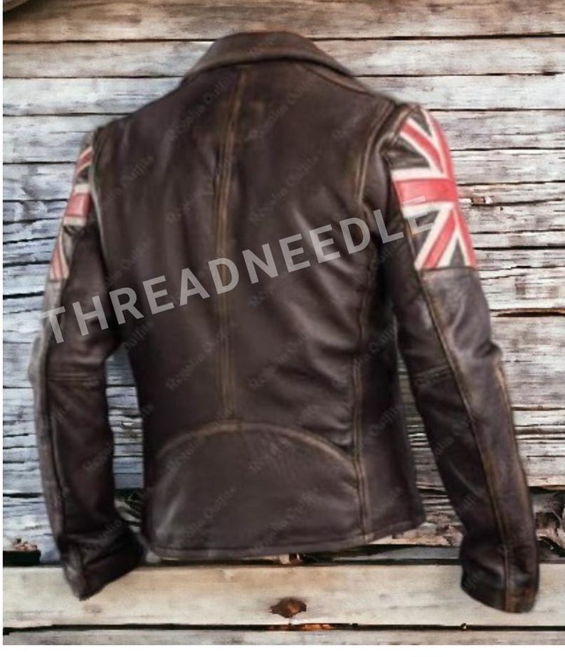 Puede incluir: Chaqueta de cuero marr&oacute;n con dise&ntilde;o de la bandera brit&aacute;nica en los hombros. La chaqueta tiene un cuello cl&aacute;sico y un acabado envejecido. El texto "THREADNEEDLE" es visible en la chaqueta.