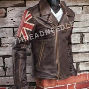 Puede incluir: Chaqueta de cuero marr&oacute;n con la bandera de la Union Jack en la manga izquierda. La chaqueta tiene cierre de cremallera, cuello con solapas y varios bolsillos. El texto "THREADNEEDLE" es visible en la chaqueta.