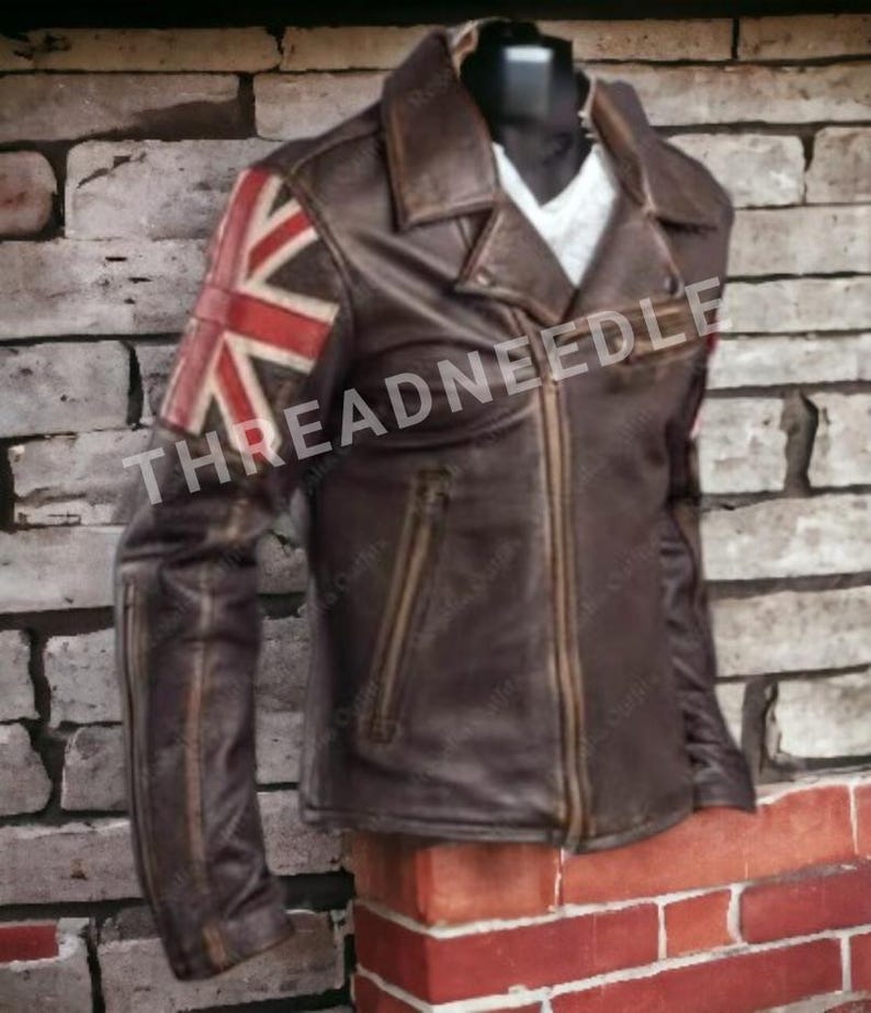 Puede incluir: Chaqueta de cuero marr&oacute;n con la bandera de la Union Jack en la manga izquierda. La chaqueta tiene cierre de cremallera, cuello con solapas y varios bolsillos. El texto "THREADNEEDLE" es visible en la chaqueta.