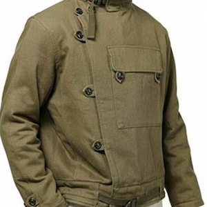 May include: Olive green jacket with a high collar and asymmetrical button closure. Features a single chest pocket and a waist belt. The jacket has multiple buttons and a military-inspired design.