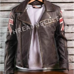 Puede incluir: Chaqueta de cuero marr&oacute;n con un dise&ntilde;o de la bandera de la Union Jack en el hombro derecho. La chaqueta tiene un estilo motero cl&aacute;sico con cuello de solapa y cremallera asim&eacute;trica. Se ve una camiseta blanca debajo.