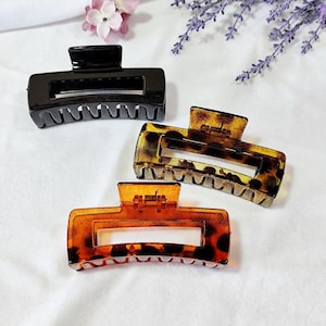 Peut inclure: Trois pinces à cheveux, une noire et deux en écaille de tortue. Les pinces en écaille de tortue ont un motif marbré brun et noir.