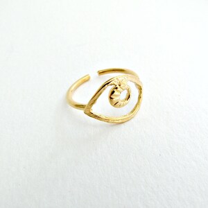 May include: Gold-toned ring with an eye-shaped design. The eye is outlined in a thin metal band and has a textured center.