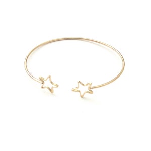 May include: Gold-coloured open cuff bracelet with star-shaped cutouts at each end. The bracelet has a simple, elegant design. The stars are hollow, adding a delicate touch. A stylish piece of jewellery for everyday wear.