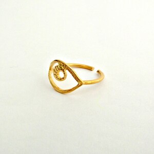 May include: Gold-toned ring with an eye-shaped design. The ring is made of metal and has a simple, minimalist style.