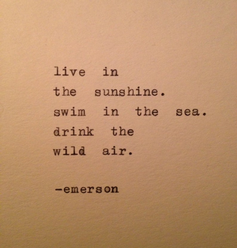 Op de afbeelding: Een zwart-wit afbeelding van een typemachine met de tekst "live in the sunshine. swim in the sea. drink the wild air. -emerson"