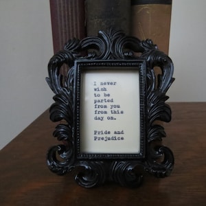 May include: A black ornate picture frame with a white background and a quote from Pride and Prejudice: "I never wish to be parted from you from this day on."