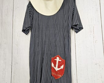 May include: A black and white striped short-sleeved dress with a red anchor patch on the front. The patch has the text "Meia Lua" on it.