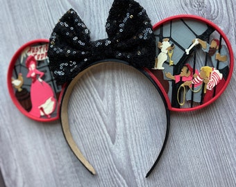 May include: Black sequin bow headband with red and white 3D ears featuring scenes from the movie "The Aristocats".