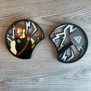 Pode incluir: Um par de orelhas de rato pretas e brancas com um design de raio. Uma orelha apresenta um personagem dos quadrinhos da Marvel, Thor, com seu martelo, Mjolnir, na outra orelha.