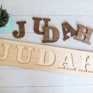 May include: Wooden name puzzle with the name "JUDAH" cut out in the wood. The letters are also included as separate pieces.