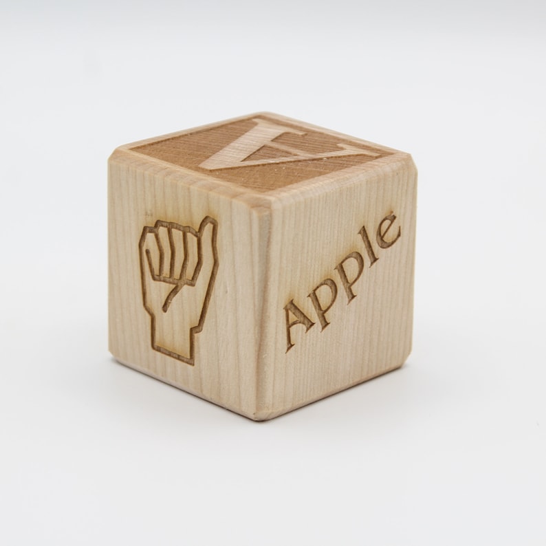May include: Wooden block with the letter V and the word "Apple" engraved on it. The block also features a sign language symbol for the letter V.
