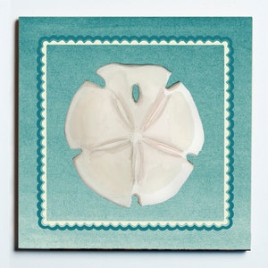 May include: A square print featuring a sand dollar in the center, painted in off-white and light brown hues. The sand dollar is set against a teal background with a scalloped border, creating a coastal theme.
