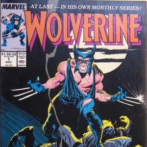May include: A comic book cover featuring Wolverine, a superhero with sharp claws, in a dark blue and black costume. The cover is black with a large, yellow, red, and white title "WOLVERINE" and the text "AT LAST - IN HIS OWN MONTHLY SERIES!" The cover also includes a price and date: "$1.50 US, $2.00 CAN, 1 NOV".