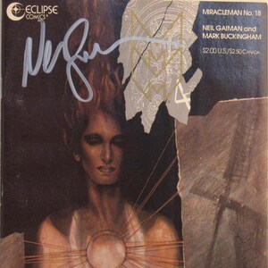 May include: A Miracleman No. 18 comic book by Neil Gaiman and Mark Buckingham, published by Eclipse Comics. The cover features a dark, illustrated portrait of a figure with a glowing orb at the chest, signed in silver ink by Neil Gaiman.