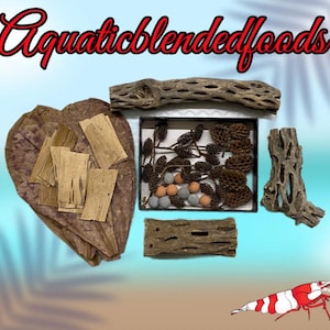May include: An assortment of aquatic habitat decorations, including wood pieces, a leaf, and a framed display of pinecones and small spheres. A red and white shrimp is also present. The text "Aquaticblendedfoods" is in red script.