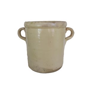 May include: A cream-colored ceramic crock with two curved handles. The antique pot has a slightly flared rim and a rounded base. The exterior has a glazed finish with visible imperfections, suggesting age and use. The crock is suitable for kitchen or home decor.