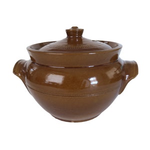 May include: A brown ceramic pot with a lid and two handles. The pot has a glazed finish and is decorated with a simple design.