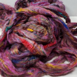 May include: A pile of colorful, hand-spun silk fibers in shades of pink, purple, red, yellow, and blue. The fibers are soft and fluffy, and they would be perfect for crafting or spinning.