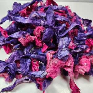 May include: A pile of shredded silk fabric in shades of purple and pink. The fabric is soft and delicate, and it would be perfect for crafting or decorating.