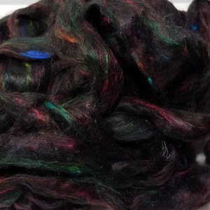 May include: Black fiber with colorful flecks of green, blue, red, and orange.