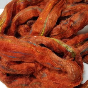 May include: A bundle of rust-colored wool fiber with colorful streaks of blue, green, and yellow.