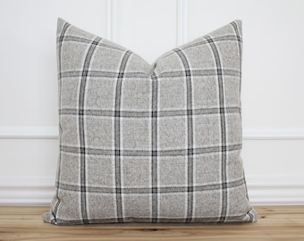 May include: A gray and black plaid throw pillow with a square pattern. The pillow is made of a soft, textured fabric.