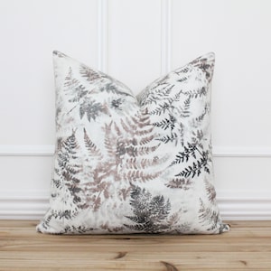 May include: A white throw pillow with a fern pattern in shades of brown and gray.