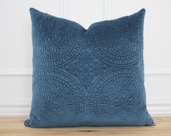 May include: A blue velvet pillow with a quilted design featuring intricate circular patterns. The pillow is soft and plush, perfect for adding a touch of elegance to any room.