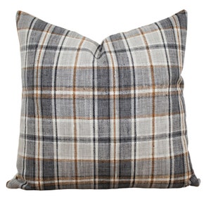 May include: A grey, brown and white plaid throw pillow with a square shape.
