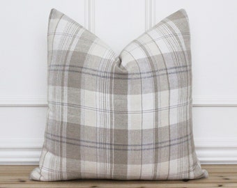 May include: A beige and white plaid throw pillow with a subtle blue stripe. The pillow is made of a soft, textured fabric and is perfect for adding a touch of farmhouse style to any room.