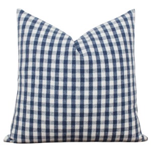 K&ouml;nnte beinhalten: Ein blaues und wei&szlig;es Gingham-Kissenbezug. Der Kissenbezug ist aus einem weichen, gewebten Stoff und hat eine quadratische Form.