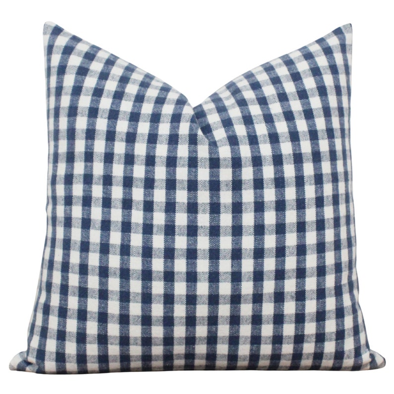 K&ouml;nnte beinhalten: Ein blaues und wei&szlig;es Gingham-Kissenbezug. Der Kissenbezug ist aus einem weichen, gewebten Stoff und hat eine quadratische Form.