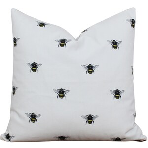 May include: White pillow cover with a repeating pattern of black and yellow bumblebees.