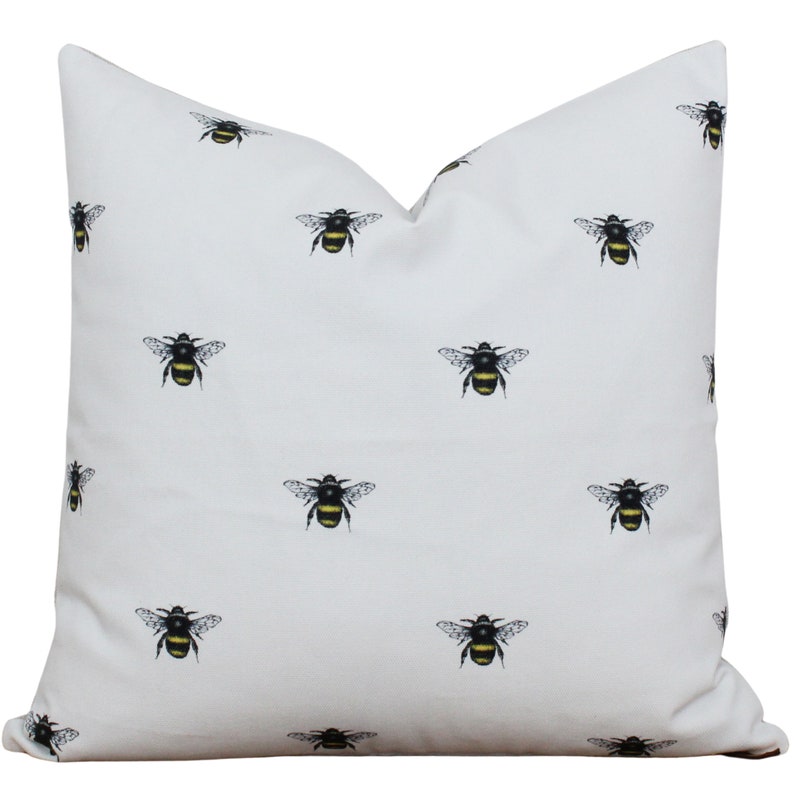 May include: White pillow cover with a repeating pattern of black and yellow bumblebees.