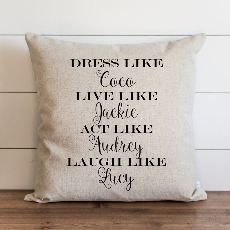 Puede incluir: Una almohada beige con texto negro que dice "V&iacute;stete como Coco, Vive como Jackie, Act&uacute;a como Audrey, R&iacute;e como Lucy".