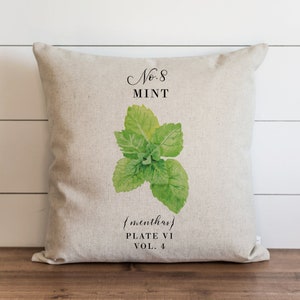 May include: A beige linen pillow with a green watercolor illustration of mint leaves. The text "No. 8 MINT {menthas} PLATE VI VOL. 4" is printed on the pillow.