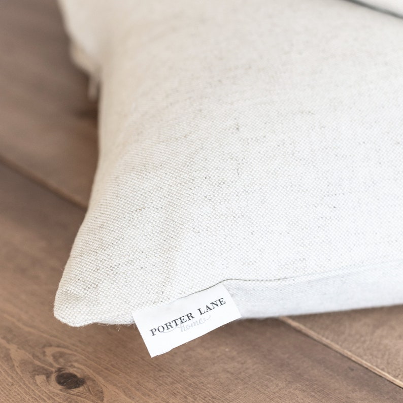 May include: A white linen pillow with a "PORTER LANE HOME" label sewn on the bottom edge.