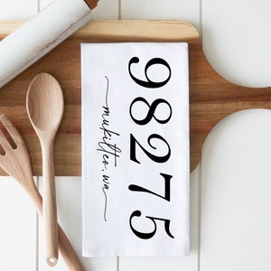 May include: White kitchen towel with black text that reads "98275 Mukilteo, WA".