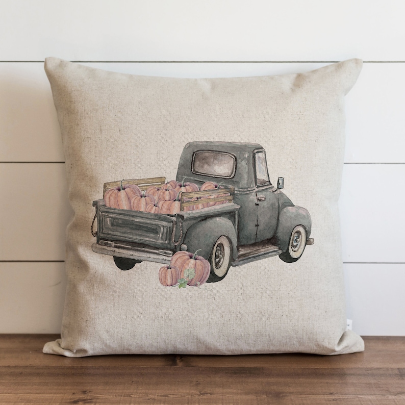 May include: A gray vintage pickup truck with a wooden bed filled with pink pumpkins. The truck is on a light gray background.