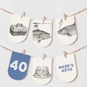 Op de afbeelding: Een decoratieve slinger met zes boogvormige kaarten aan een touwtje. De kaarten tonen zwart-witillustraties van een viskoffer, een hengel met een baars, een forel, een vissershoed met kunstaas, en blauwe kaarten met de tekst 40 en MARK'S 40TH.