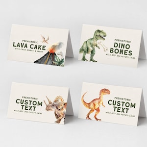 May include: Four folded place cards with dinosaur illustrations and text. The cards read "Prehistoric Lava Cake", "Prehistoric Dino Bones", and "Prehistoric Custom Text". The illustrations include a volcano, a T-Rex, a Triceratops, and a Velociraptor.