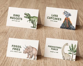 Może przedstawiać: Cztery składane białe papierowe etykiety na żywność z ilustracjami dinozaurów i tekstem. Etykiety zawierają napisy DINO NUGGETS WITH AIOLI DIP, LAVA CUPCAKES WITH CREAM, FOSSIL FRIES WITH TOMATO SAUCE oraz PREHISTORIC PUNCH GINGER & LIME w ciemnozielonym kolorze.