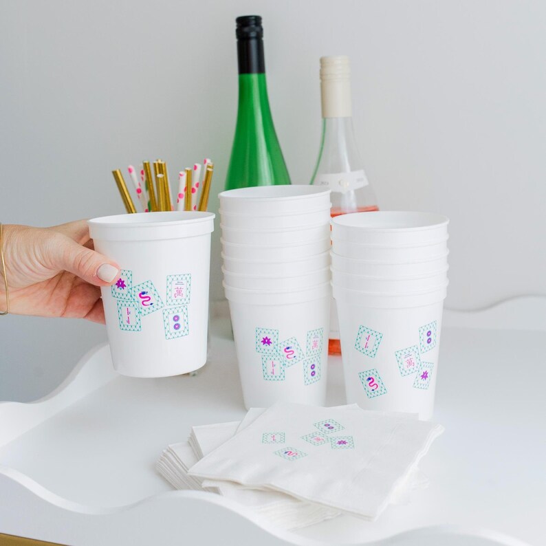 Stack of Mahjong party cups on bar cart with colorful straws and wine bottles