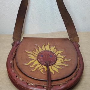 May include: A handmade, wooden cutting board with a natural wood grain. The board is rectangular with a rounded handle and measures approximately 18 inches long and 12 inches wide.