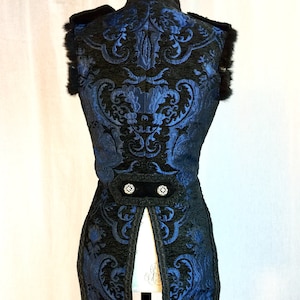 May include: A blue and black brocade vest with a long tail. The vest has a black velvet trim and two silver buttons.