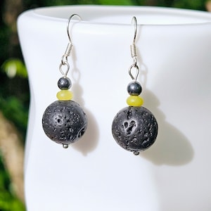 May include: A pair of silver dangle earrings with black lava rock beads and yellow beads. The earrings have a simple design and are perfect for everyday wear.
