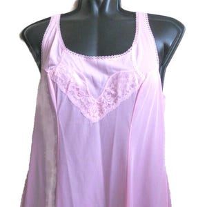 May include: A pale pink vintage slip dress with a scoop neckline and delicate lace trim. The sleeveless nightdress features a V-shaped lace detail on the bodice and a flowing, lightweight design, suitable for sleepwear or lingerie.